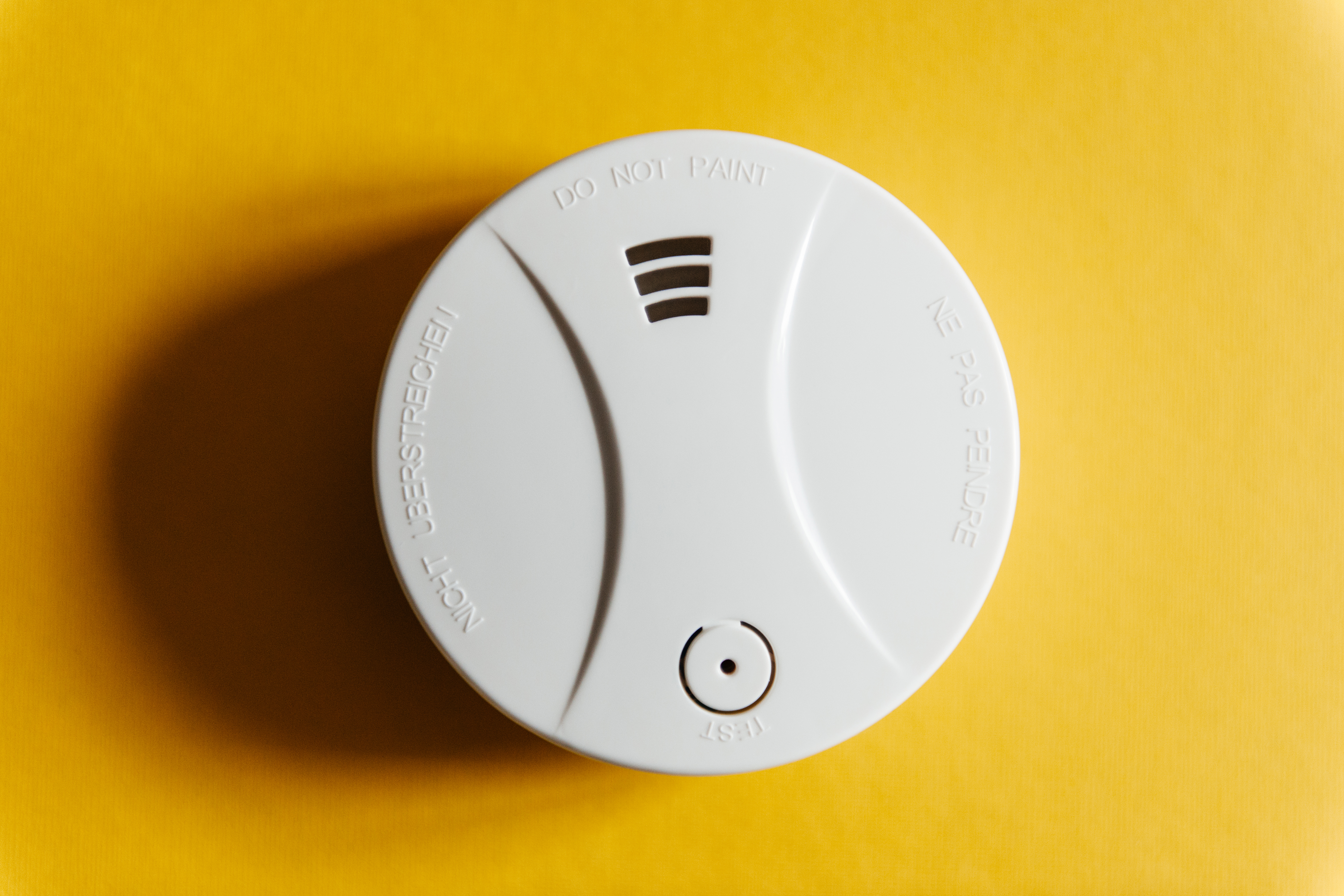 A smoke detector on a yellow background